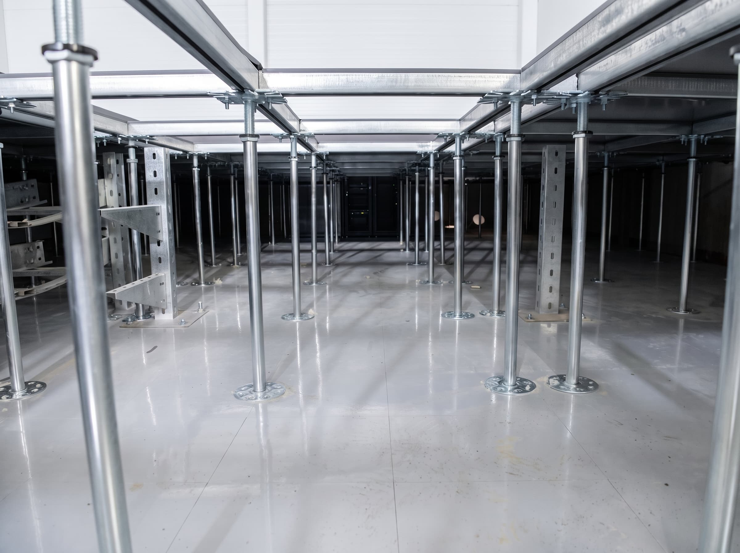 Underfloor void of the Aktau server room — adjustable TR pedestals, server racks beyond